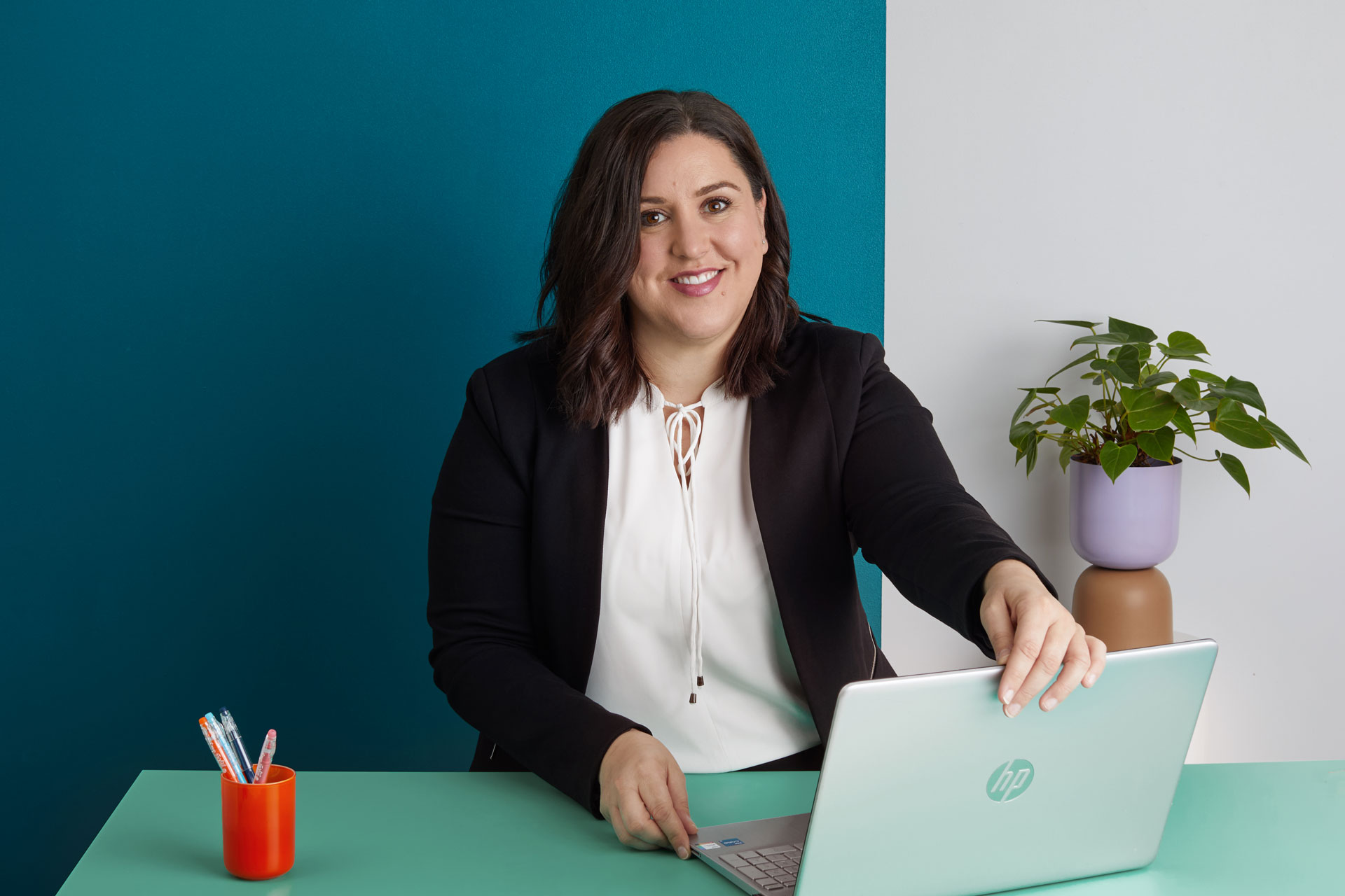 Lady (Sacha Mastras) sitting at a table opening her laptop, symbolisng blog about meeting Sacha Mastras at The Family Law Co