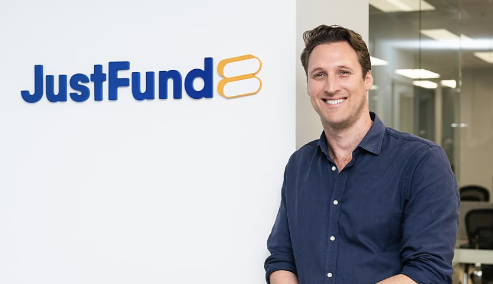 A man smiling while standing in front of a JustFund sign, representing support for individuals navigating family law and separation.